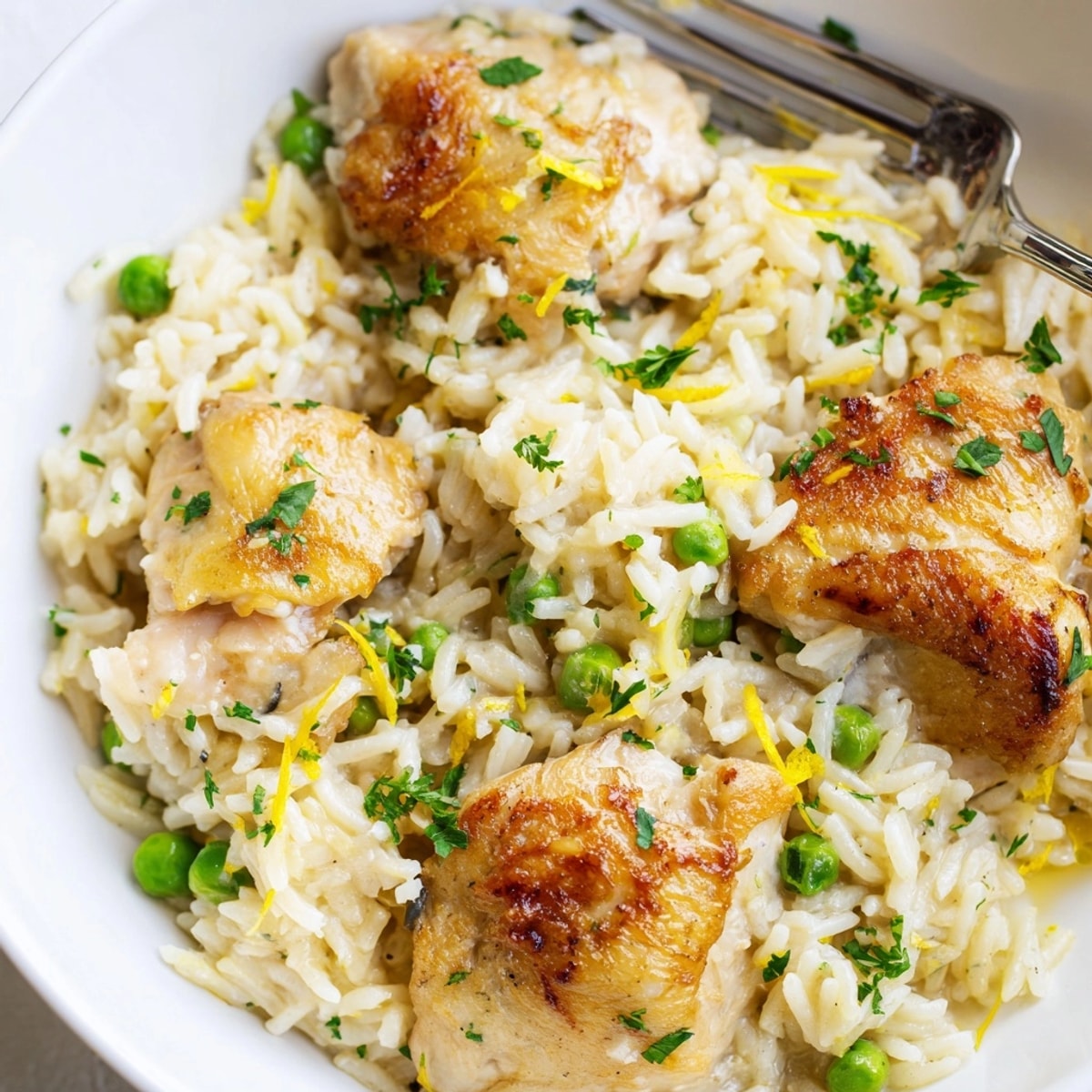 Creamy lemon chicken and rice served in one pot, garnished with fresh parsley for a cozy dinner.