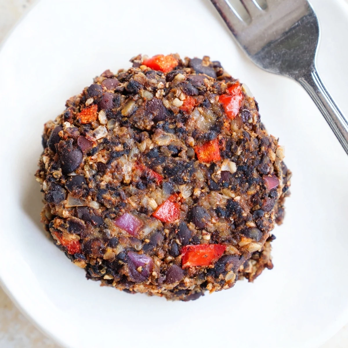 Homemade black bean burgers on a plate, looking crispy, with the aroma of cumin, ready to enjoy.