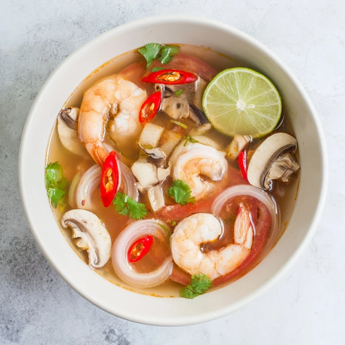 Fragrant Spicy Tom Yum Soup, garnished with cilantro, offering a burst of Thai flavors.