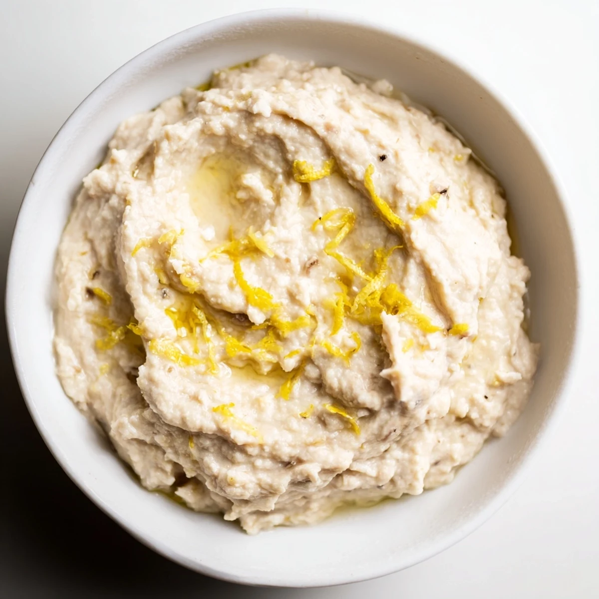 Creamy White Bean Dip in a rustic bowl, drizzled with golden olive oil and fresh parsley, served with warm pita bread.  