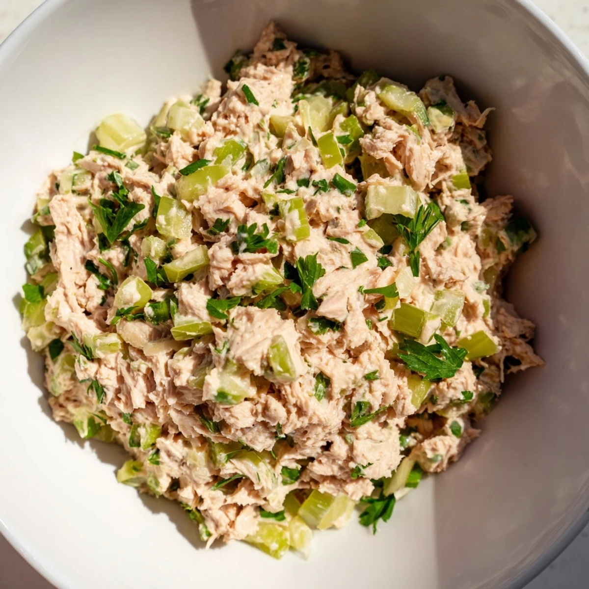 Close-up of Spicy Zesty Tuna Salad piled high on a sandwich, showing flaky tuna and crisp greens.
