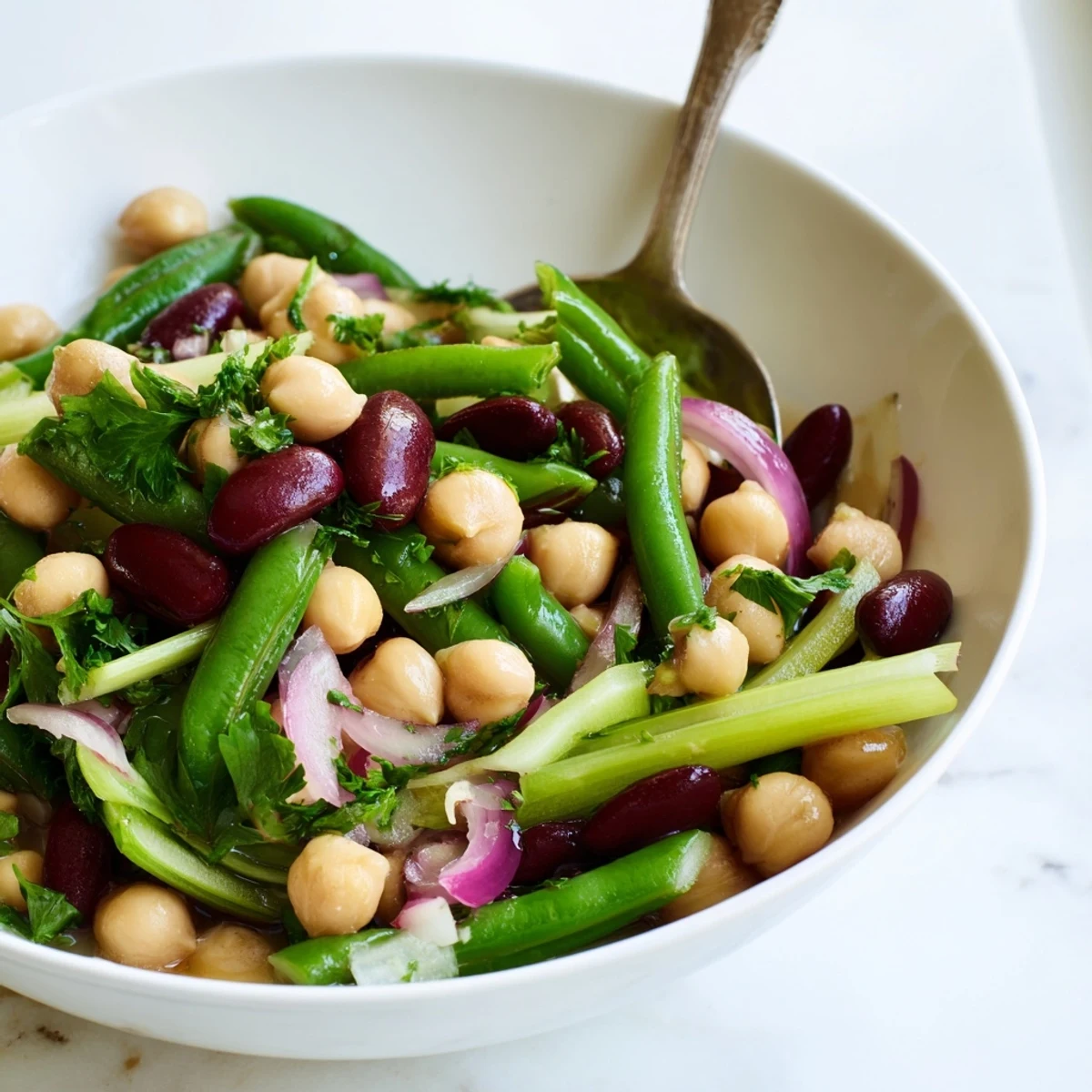 Chilled Three-Bean Salad featuring crunchy beans, crisp celery, and fresh parsley, served as a refreshing vegetarian side dish.