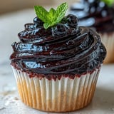 Swirled Black Currant Frosting on a vanilla cupcake, garnished with fresh berries, with a silky, tangy-sweet texture.