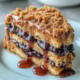 Warm slices of PB and J Cake With Black Currant Sauce drizzled generously over the top for a sweet finish.
