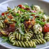 Fresh summer pasta salad with pesto, cherry tomatoes, and mozzarella, bursting with bright flavors and creamy textures, ideal for picnics and warm-weather dining.