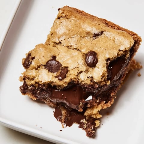 Close-up of a cut The Ultimate Gooey Chocolate Chip Cookie Bar, showcasing melty chocolate chips and a chewy texture.