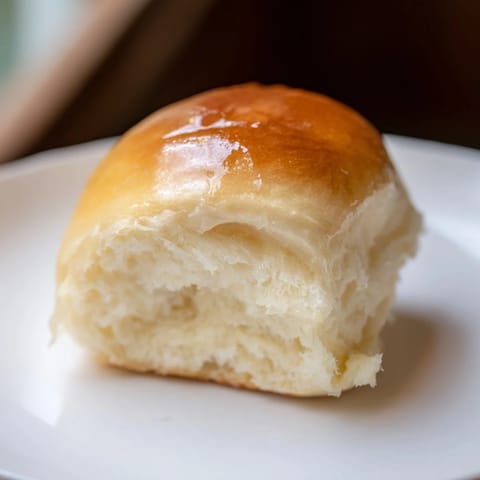 Warm Quick-Rise Dinner Rolls topped with melted butter, perfect for sopping up gravy at a family dinner.