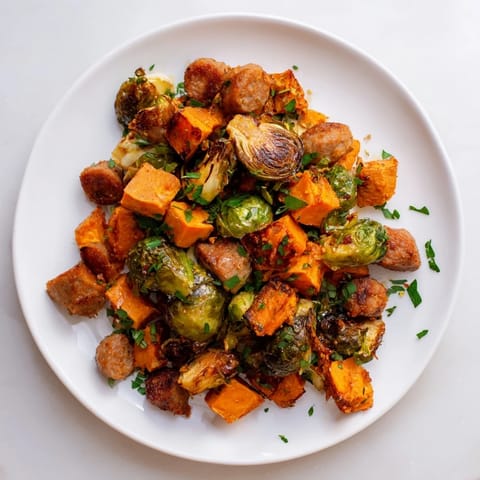 Golden brown sheet pan sausage, sweet potatoes, and Brussels sprouts, ready for a delicious, healthy dinner.