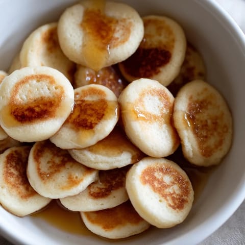 Tiny, perfectly cooked Fluffy Pancake Cereal ready to eat, served with sweet maple syrup.