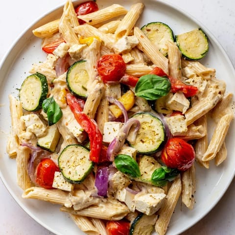 Creamy baked feta pasta with herbs, served in a dish, fresh basil leaves on top.
