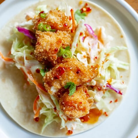 Close-up of crispy hot honey chicken tacos, appealingly topped with fresh cilantro and a spicy drizzle.
