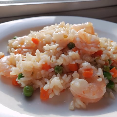 Steam rises from the wok as fluffy jasmine rice mingles with sautéed shrimp, vibrant peas, and crisp spring onions in this Shrimp Garlic Fried Rice.