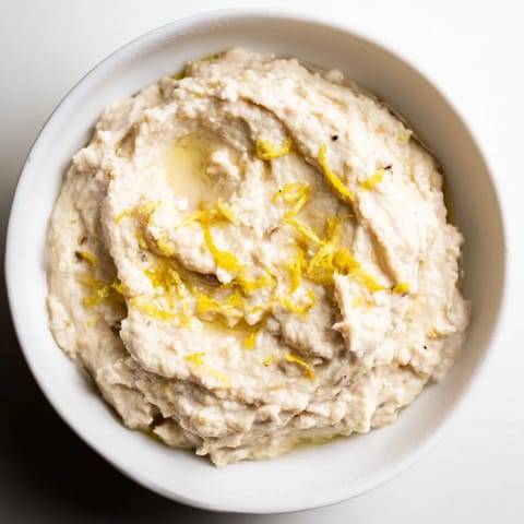 Creamy White Bean Dip in a rustic bowl, drizzled with golden olive oil and fresh parsley, served with warm pita bread.  