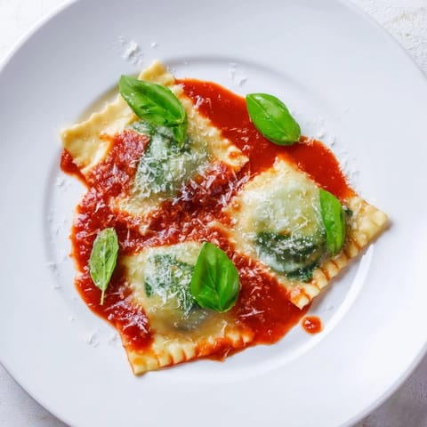Freshly cooked Spinach Ricotta Ravioli topped with extra Parmesan on a rustic plate.