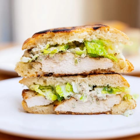 Juicy Caesar Chicken Sandwich with fresh romaine and melted Parmesan, ready to serve on a rustic wooden board.