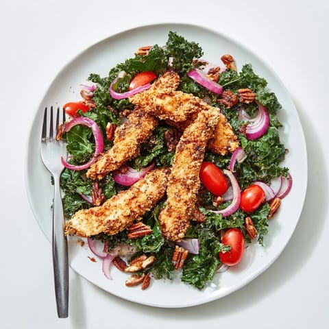 A hearty Crispy Chicken Kale Salad features golden-brown breaded cutlets over fresh greens, tossed with toasted pecans and tangy vinaigrette.