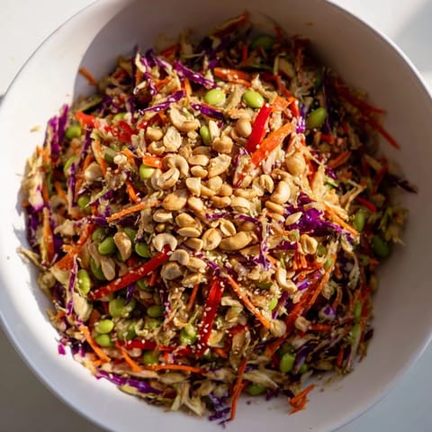 The vibrant Edamame Crunch Chicken Salad served in a white bowl, topped with toasted sesame seeds and crunchy cashews, ready for a light lunch.