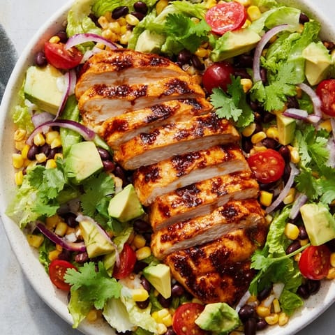 Taco salad featuring juicy honey lime chicken, black beans, cherry tomatoes, and crispy tortilla strips.