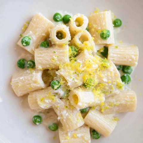 Vibrant spring pea and lemon ricotta pasta in a bowl, ready to serve with a sprinkle of lemon zest.  