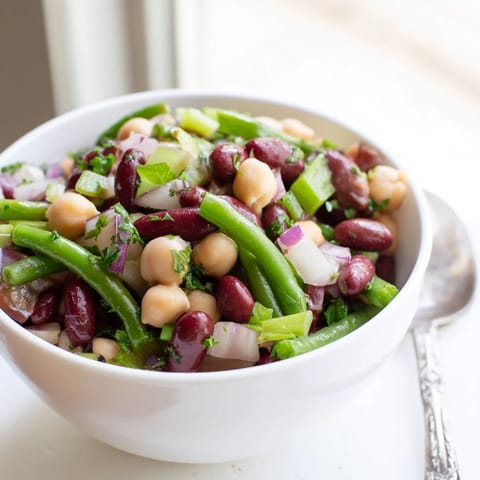 A vibrant Three-Bean Salad with green, kidney, and chickpeas tossed in a tangy apple cider vinairette, perfect for picnics and potlucks.
